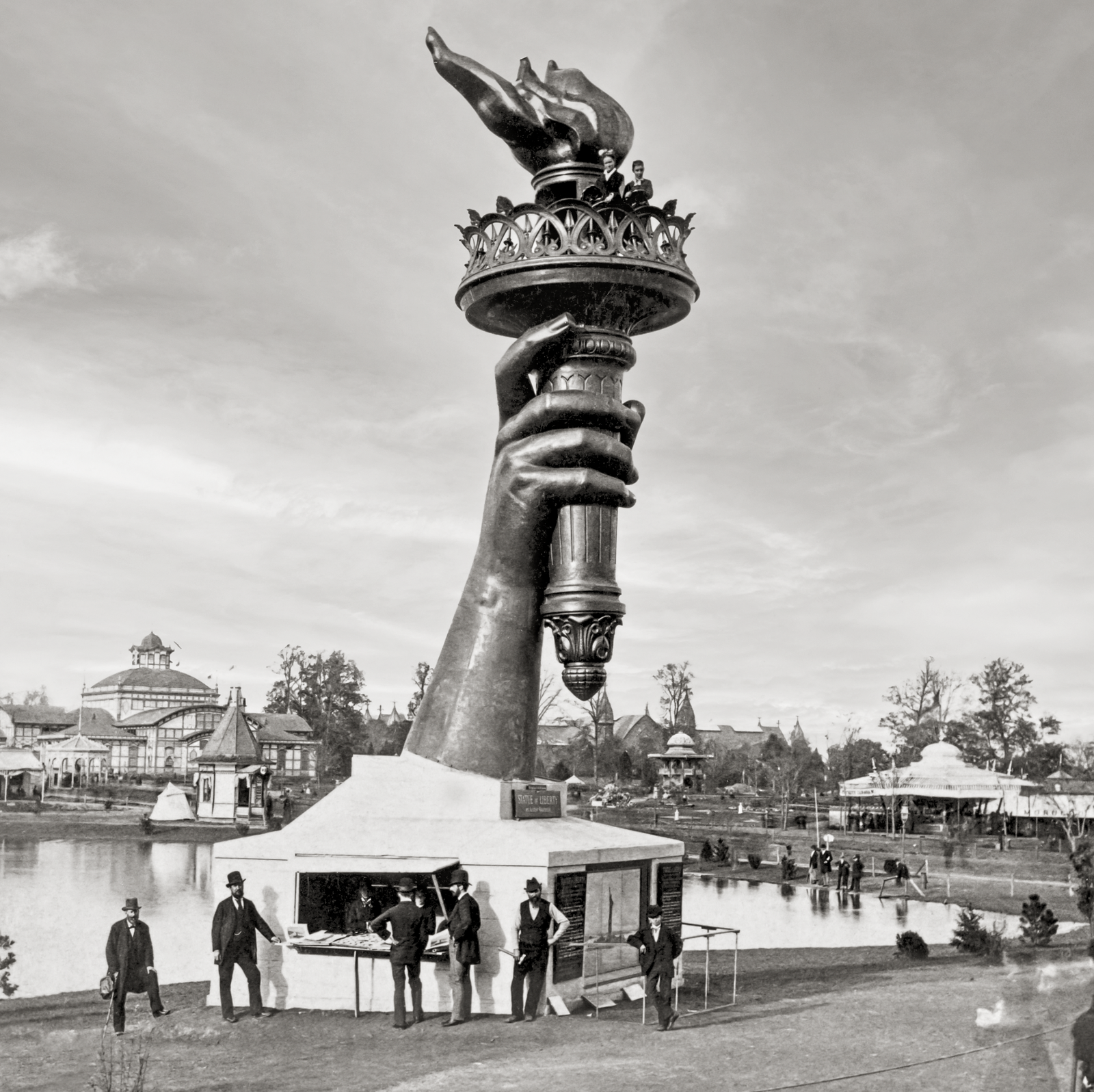A closeup of the arm with people standing on the flame.