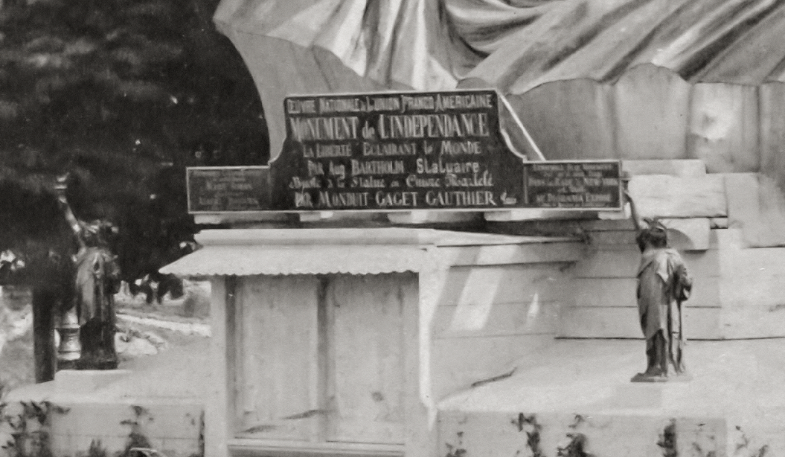 The closeup of a sign below the head of the Statue of Liberty.