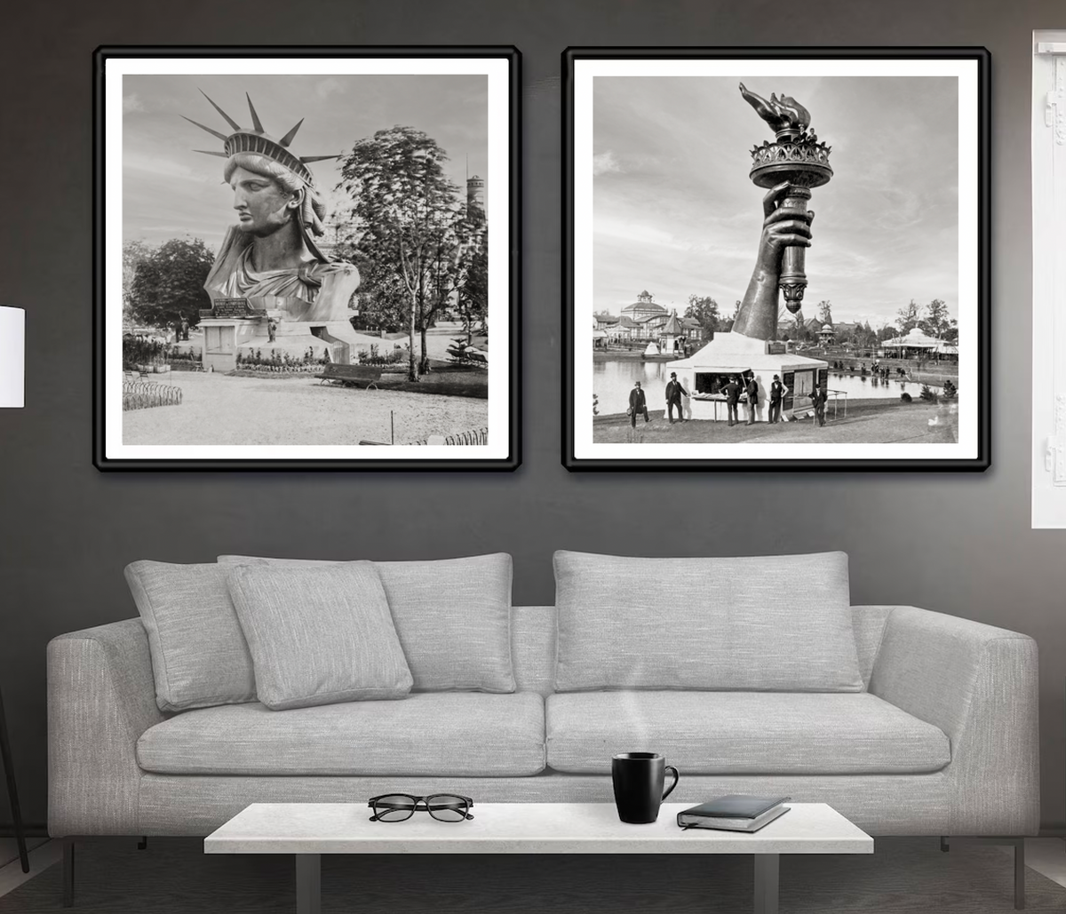 The two photos of the Statue of Liberty (the head and arm) are shown framed and above a couch.