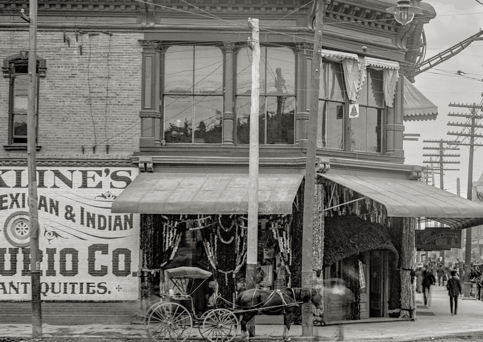 Side view of a horse and carriage parked outside a Mexican & India Curio Co. Antiques on El Paso Street.